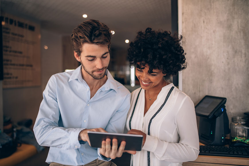 man showing woman a restaurant system on ipad
